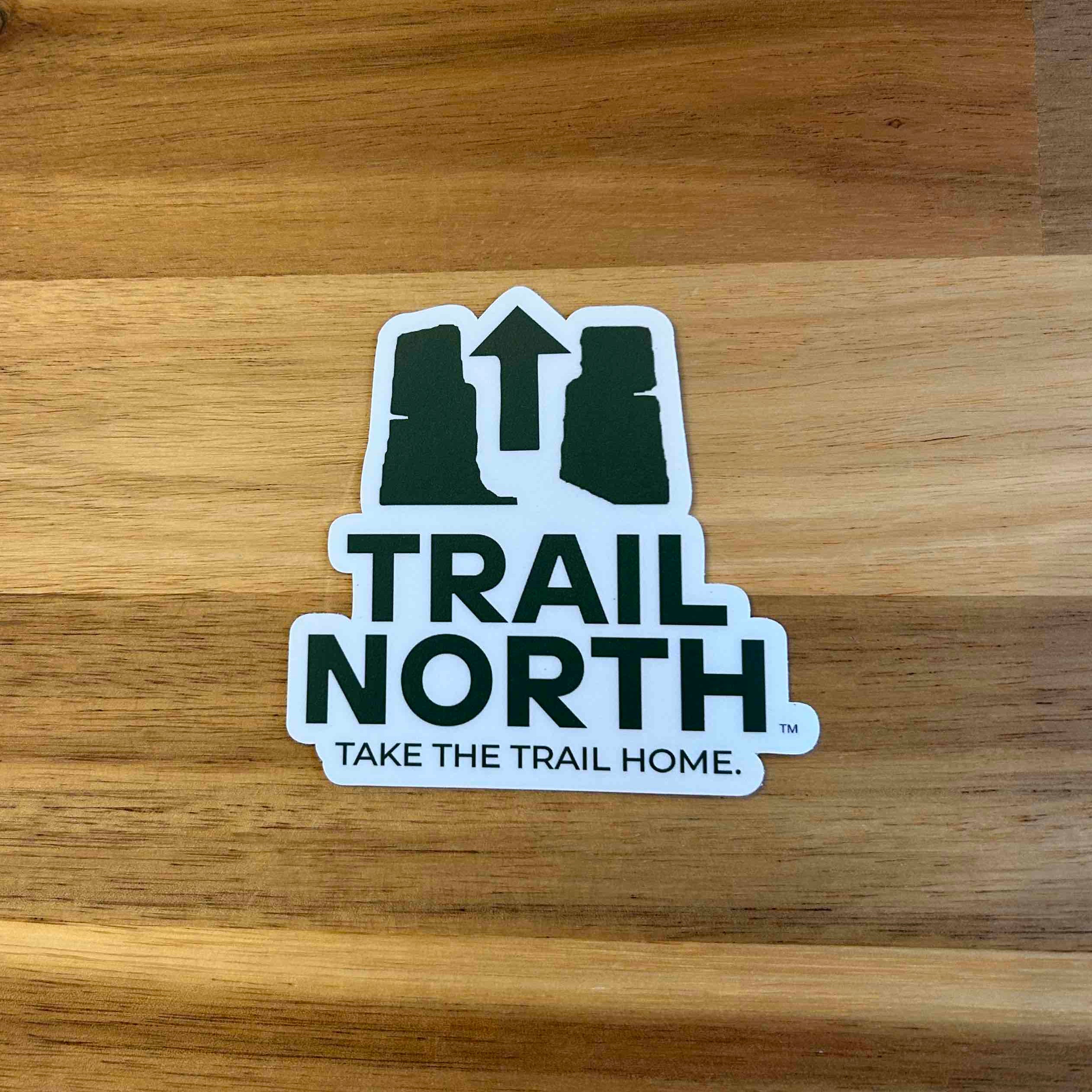 Sticker with 'Trail North' text on a wooden surface